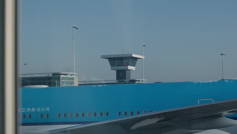 Blue-airplane-with-the-control-tower-in-the-background-at-Rotterdam-airport-in-The-Netherlands