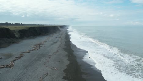 Luftumkehr-Entlang-Des-Steinigen-Strandes,-Während-Die-Wellen-Hereinrollen---Hakatere-Beach-Schwemmklippen---Neuseeland