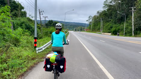 Women-in-the-sunny-day-cycling-in-the-road-of-Nan-province,-Thailand
