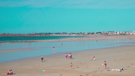 People-enjoying-a-day-out-at-the-beach-during-low-tide-in-Saint-Malo,-Brittany