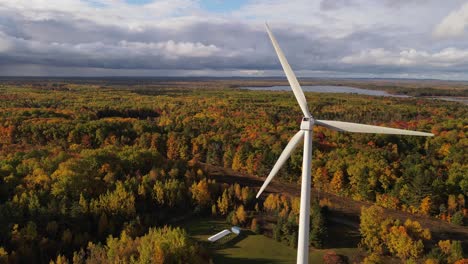 Wind-turbine-working-in-autumn-colored-woodland-area-of-USA,-aerial-view