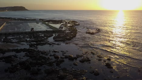 Beach-sunrise-aerial:-morning-clean-of-Mereweather-ocean-baths,-AU