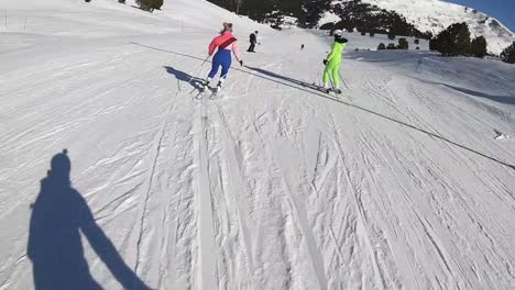 Skiers-in-colorful-ski-suits-going-down-a-slope-at-a-ski-resort-in-the-Alps