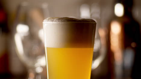 Close-up-of-craft-Beer-being-poured-in-to-a-pint-glass-to-top-it-off,-light-background