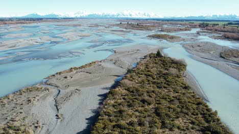 Aerial-reveal-of-majestic-southern-alps-from-beautiful-Rakaia-River-on-a-clear,-calm-mid-winter's-day