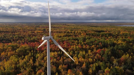 Wind-turbine-operating-in-colorful-woodland-area-in-autumn-season,-aerial-view