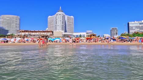 Crowdy-beaches-in-front-of-the-enjoy-hotel-and-Punta-del-Este-skyline,-beginning-of-January-2023,-during-high-season-in-Uruguay