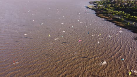 Luftaufnahmen-Von-Oben-Nach-Unten,-Die-Eine-Menge-Kitesurfer-Zeigen,-Die-An-Sonnigen-Tagen-In-Buenos-Aires-Auf-Dem-Fluss-Surfen