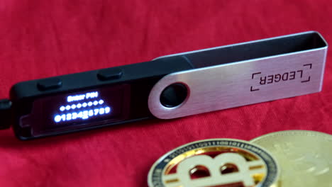 Ledger-Nano-with-led-light-showing-enter-pin-and-bitcoin-on-a-red-cloth