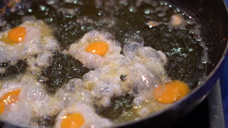 closeup-of-a-man-frying-small-quail-eggs-in-a-pan-with-plenty-of-oil