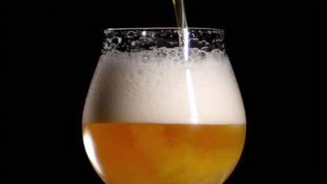 Zeitlupe-Nahaufnahme-Von-Craft-Beer,-Das-In-Ein-Tulpenglas-Gegossen-Wird,-Schwarzer-Hintergrund