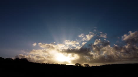 Rising-Aerial-View-of-Dramatic-Sunrise-with-Light-Rays-Through-Cloudscape-with-Tree-Silhouettes---Drone-Shot-UK-4K