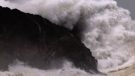 Big-huge-ocean-wave-crashing-rock-on-coast,-slow-motion,-Nazare-in-Portugal