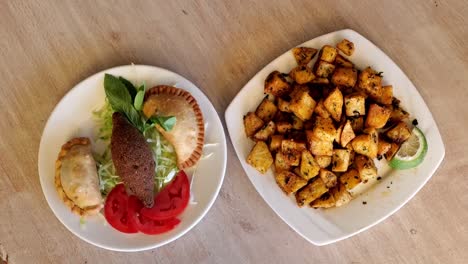 Top-View-Of-Arabian-Traditional-Plates,-Kebbe,-Pastries,-Tomato-And-Spicy-Potato-Plate