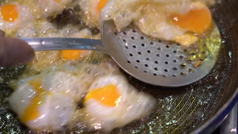 closeup-of-a-man-frying-small-quail-eggs-in-a-pan-with-plenty-of-oil