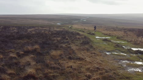 Aerial-View-of-Athlete-Runner-Training-Over-Countryside-Moorland-in-Exmoor---Sideways-Drone-Shot-UK-4K