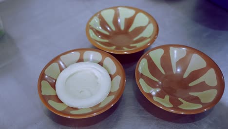 Person-Hand-Spreading-Hummus-Around-Dish,-Designing-Plate