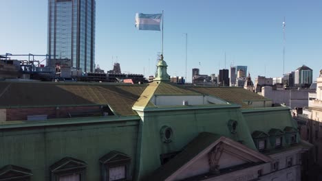 Argentinische-Fahnenschwingen-Auf-Dem-Dach-Des-Argentinischen-Bankgebäudes-Mit-Wolkenkratzer-Im-Hintergrund