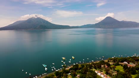 Aerial-Lake-and-Volcano-Backwards-Ascent-from-Coastline---Lake-Atitlan,-Panajachel,-Guatemala