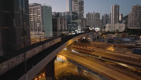 Follow-shot-of-train-passing-overpass-and-traffic-in-Kwai-Chung-District-of-Hong-Kong-at-blue-hour