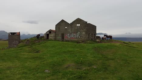 Abandoned-damaged-old-stone-building-in-Iceland,-vandalized-with-graffiti,-aerial-view