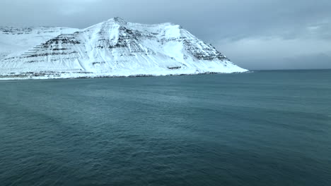 An-Einem-Bewölkten-Tag-Rollen-Große-Wellen-Ans-Ufer-Mit-Den-Hohen-Schneebedeckten-Gipfeln-Der-Isländischen-Natur-Im-Hintergrund