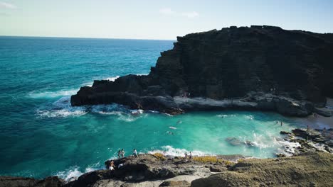 People-swimming-and-cliff-jumping-at-Halona-Blow-Hole,-Honolulu,-Hawaii-on-a-bright-sunny-day-in-the-turquoise-blue-pacific-ocean