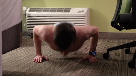 Young,-white,-shirtless,-male-doing-50-pushups-in-his-hotel-room-by-the-AC-unit-in-jeans