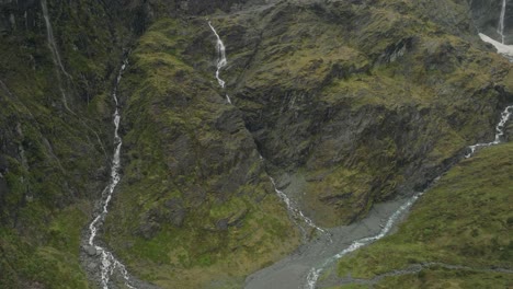 Mountain-streams-flowing-into-New-Zealand-natural-valley,-seen-from-above