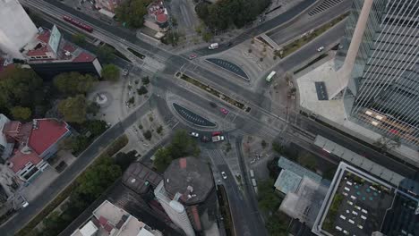 Close-up-aerial-view-of-a-roundabout-with-passing-cars,-bicycles,-buses-and-people-in-Mexico-City
