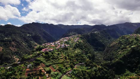 Vista-Aérea-Del-Pueblo-En-La-Cima-De-Un-Valle-De-Montaña-En-Un-Exuberante-Paisaje-Verde