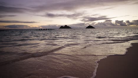 A-group-of-Canoers-rowing-past-the-Mokolua-islands-off-of-Lanikai-beach,-Kailua,-Hawaii-at-Sunrise-in-slow-motion