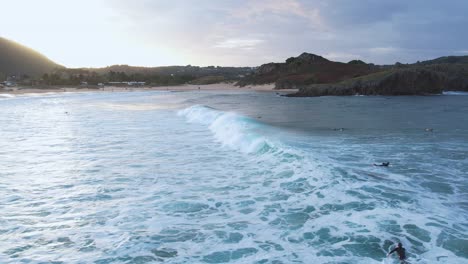 Luftvideo-Zeigt-Surfer,-Die-Bei-Sonnenuntergang-In-Kantabrien,-Spaniens-Malerischem-Küstenparadies,-Auf-Wellen-Reiten
