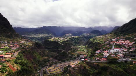 Aerial-panorama-of-town-in-volcanic-green-mountain-valley-landscape,-Madeira