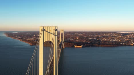 Aerial-tracking-shot-passing-the-Verrazzano-Narrows-Bridge-with-Staten-Island-in-the-background,-fall-sunset-in-NY,-USA