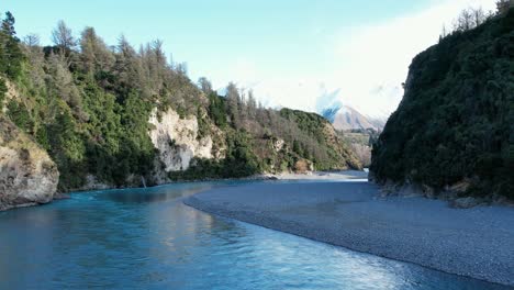Low-aerial-traverse-across-beautiful-Rakaia-River-Gorge---early-morning,-mid-winter,-fresh-snow-on-Mount-Hutt