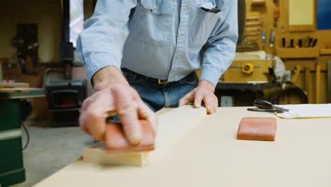 Woodworker-sands-a-piece-of-wood-in-his-workshop