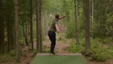 Disc-Golfer-Lanza-Un-Tiro-De-Apertura-De-Revés-Desde-El-Tee-En-Un-Denso-Bosque-Finlandés