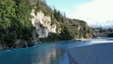 Low-aerial-hover-near-very-small-waterfall---Rakaia-River-Gorge---early-morning,-mid-winter