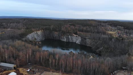 Drone-shot-of-a-water-filled-mining-pit-in-Stråssa,-Sweden