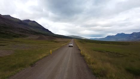 Journey-across-Iceland-in-SUV,-aerial-follow-shot-with-mountains-in-background
