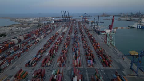 Wide-Aerial-view-of-shipping-port-at-dusk,-evening-in-Valencia,-Spain