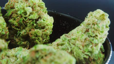 Macro-Green-Dried-Marijuana-Buds-Close-Up-concept-Shot,-pile-of-dried-marijuana-plants,-orange-trichomes-strains,-in-small-black-shiny-bawl,-on-a-rotating-stand,-studio-lights,-slow-motion,-4K-video
