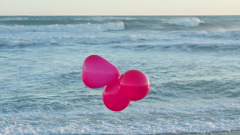 Drei-Rote-Luftballons-Tanzen-Im-Wind,-Während-Sich-Im-Hintergrund-Meereswellen-Brechen
