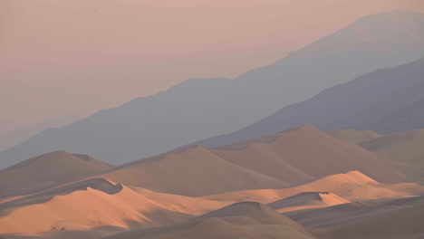 Telephoto-landscape-of-massive-sand-dunes-with-mountain-range-behind