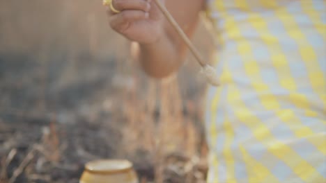 Dreamy-slow-motion-close-up-shot-of-a-young-beautiful-Indian-woman-dipping-a-brush-into-a-pot-and-painting-a-broken-clay-pot-in-her-hands-outdoors