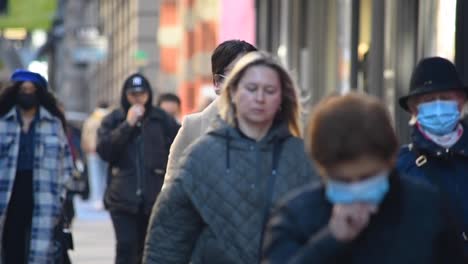 Compression-shot-of-people-walking-on-NYC-sidewalk,-some-wearing-masks