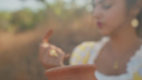 Out-of-focus-slow-zoom-in-to-delicate-hand-of-young-attractive-Indian-woman-holding-a-broken-shard-of-pottery