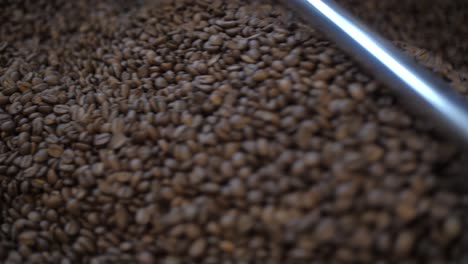 roasted-coffee-beans-cooling-down-mixing-on-plate,-production-in-roastery-detail