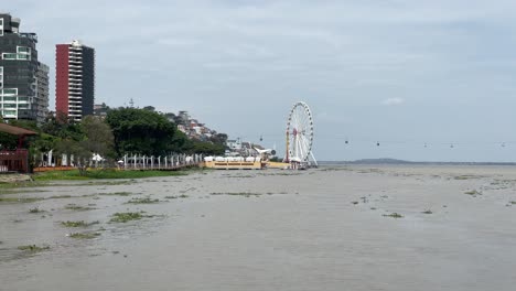 A-view-of-Malecon-Simon-Bolivar,-the-Guayas-River,-the-ferry-wheel-La-Perla-and-the-Aerovia-in-a-cloudy-day